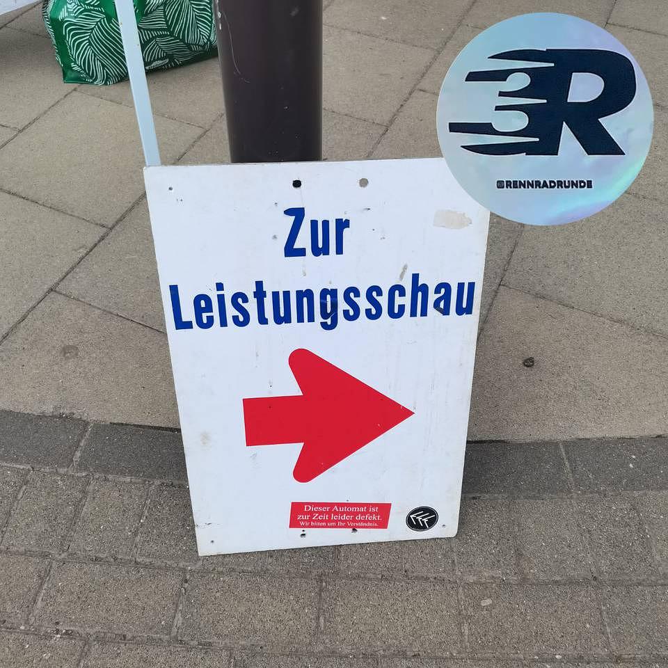 Schild mit Aufschrift "Zur Leistungsschau" darunter ein roter Pfeil